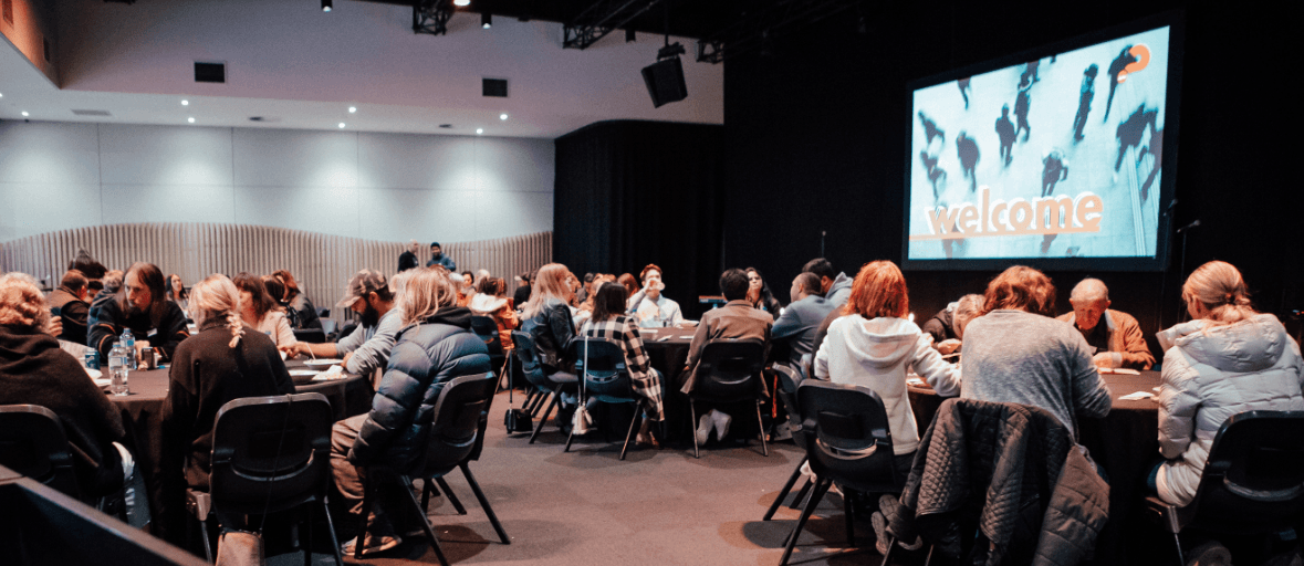 Lots of people sitting at round tables in the Chapel at LIFE Central during the Alpha course, listening and sharing with each other